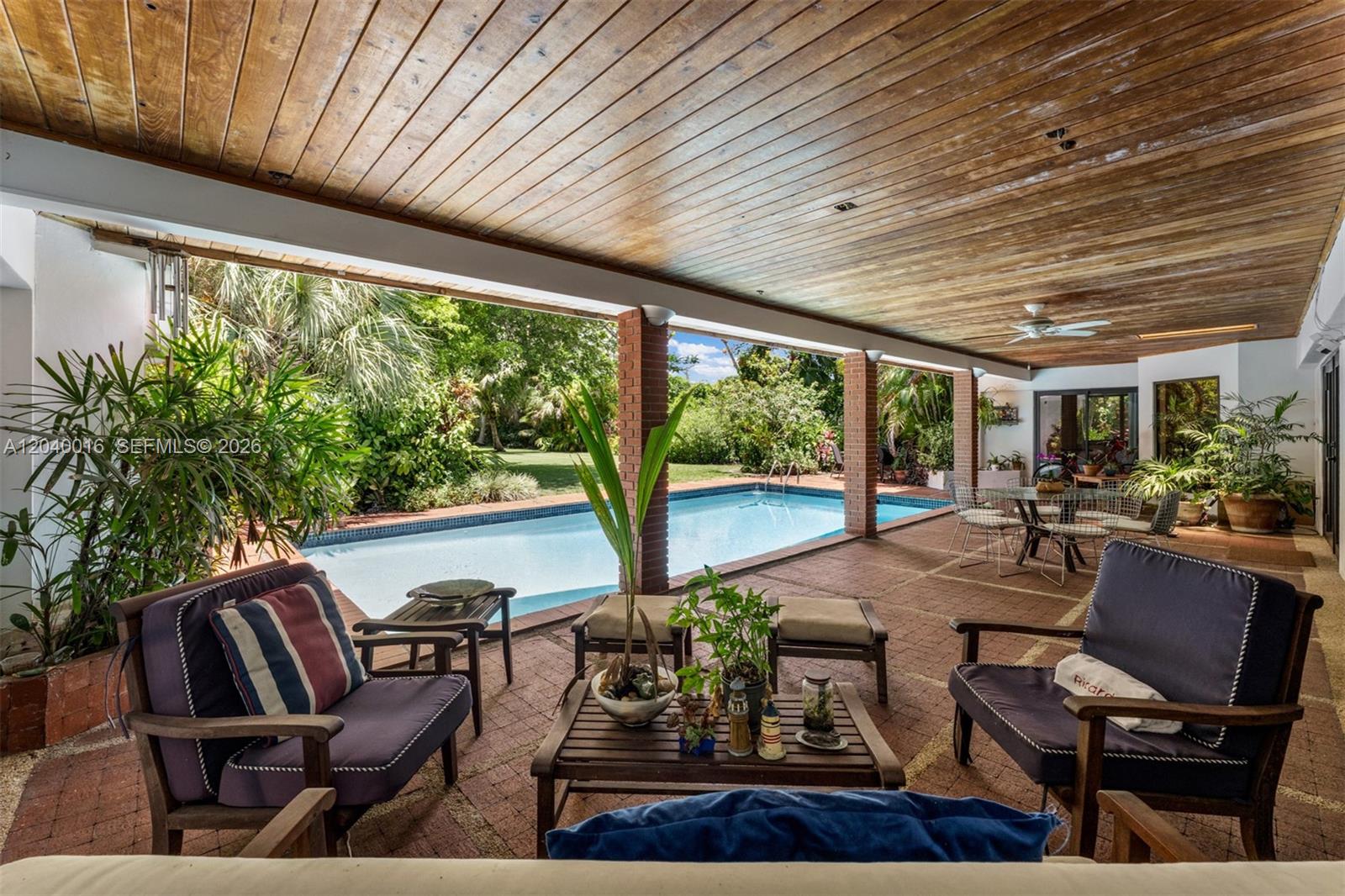 A covered brick patio features outdoor seating, a wooden ceiling, and a swimming pool view — 11100 SW 67th Ave, Pinecrest FL 33156, PINECREST, FL