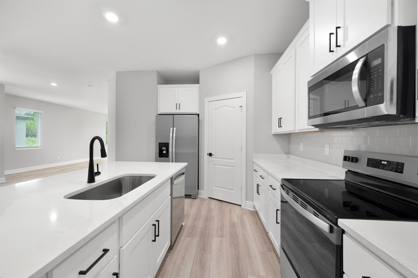 A modern kitchen features white cabinets, stainless steel appliances, a kitchen island, and light flooring — 1611 Gaiety Way, Fort Pierce FL 34947, FORT PIERCE, FL