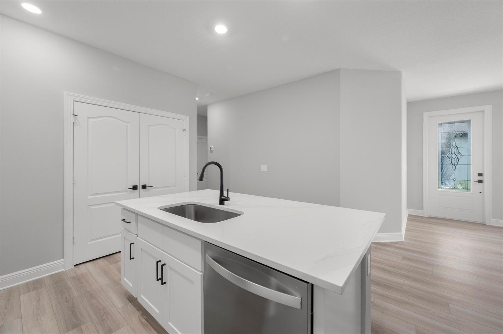 A kitchen island with a stainless steel sink and dishwasher sits in a white room — 1611 Gaiety Way, Fort Pierce FL 34947, FORT PIERCE, FL
