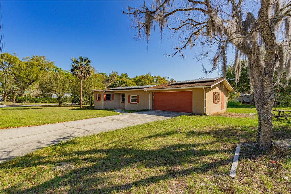 A single-story house with a tan exterior, a red garage door, and a concrete driveway — 805 S STONE STREET, DELAND, FL