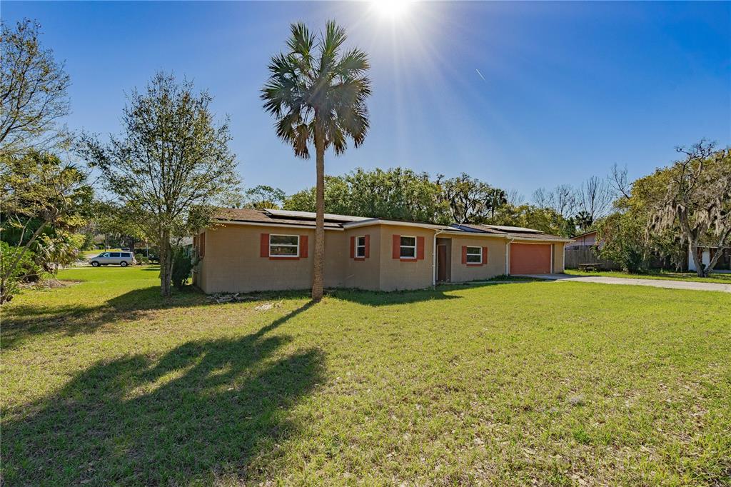 A single-story tan house with a palm tree in the front yard under a sun — 805 S STONE STREET, DELAND, FL