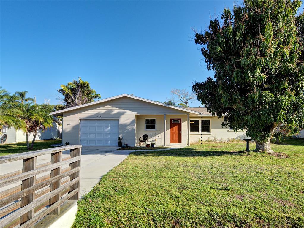 A single-story house with light siding, a one-car garage, and a large tree in front — 836 STEWART STREET, ENGLEWOOD, FL