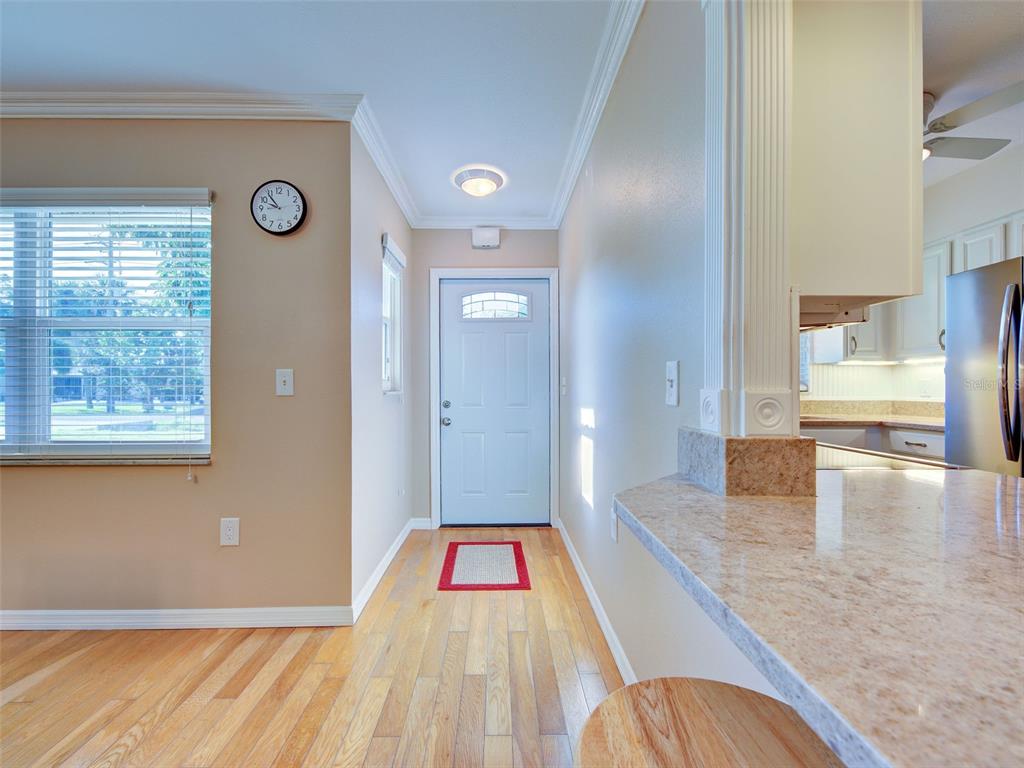 An entryway with hardwood floors leads to a white front door near a kitchen counter — 836 STEWART STREET, ENGLEWOOD, FL