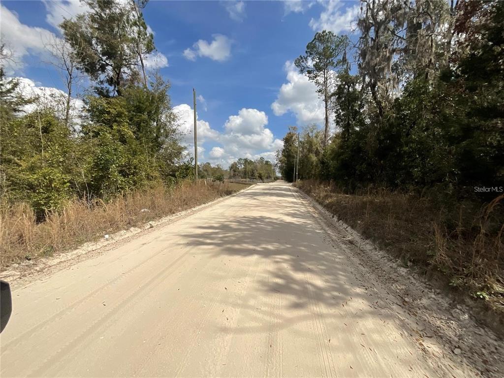 A dirt road stretches through a wooded area under a blue sky with scattered clouds — SW OLD SPANISH ROAD, FORT WHITE, FL