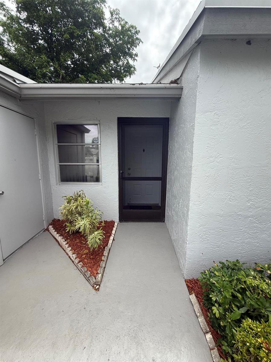 A concrete walkway leads to a front door with a screen door and a window — 18528 Hidden Way, Boca Raton FL 33496, BOCA RATON, FL