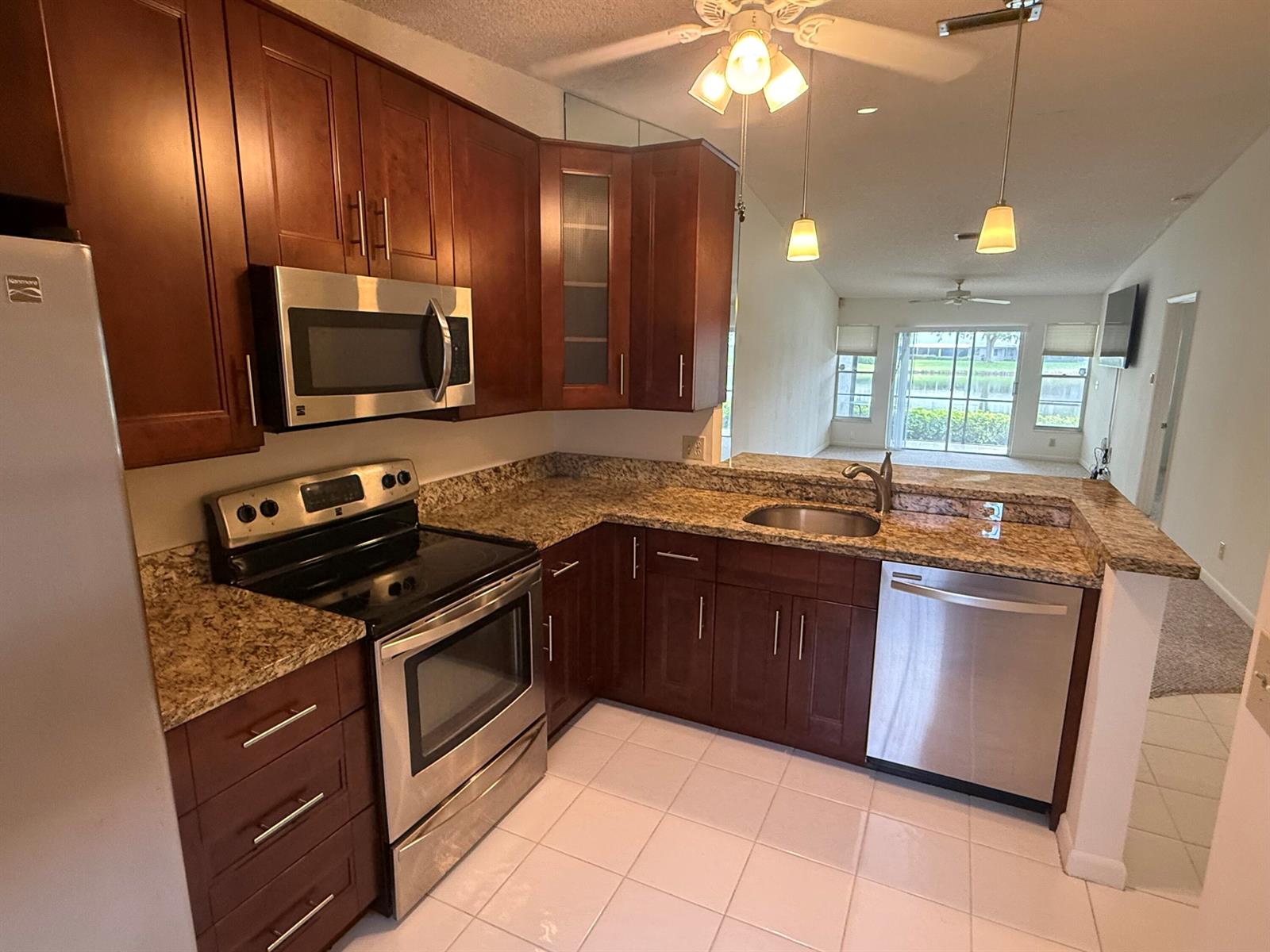 A kitchen with dark wood cabinets, granite countertops, stainless steel appliances, and tile flooring — 18528 Hidden Way, Boca Raton FL 33496, BOCA RATON, FL