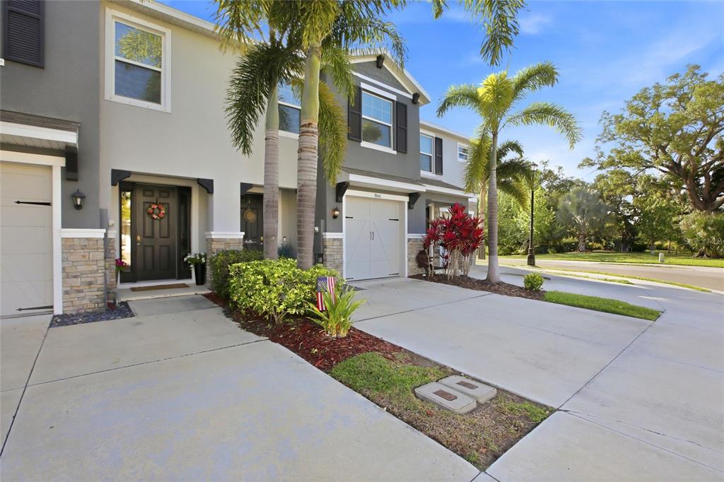 A two-story townhouse exterior features a garage, stone accents, and palm trees — 8660 PALMER PARK CIRCLE, SARASOTA, FL