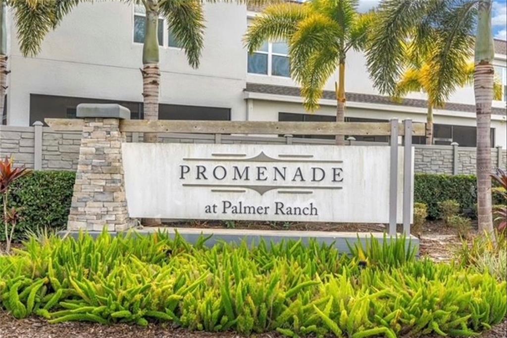 A stone and concrete sign for Promenade at Palmer Ranch stands before a residential building — 8660 PALMER PARK CIRCLE, SARASOTA, FL