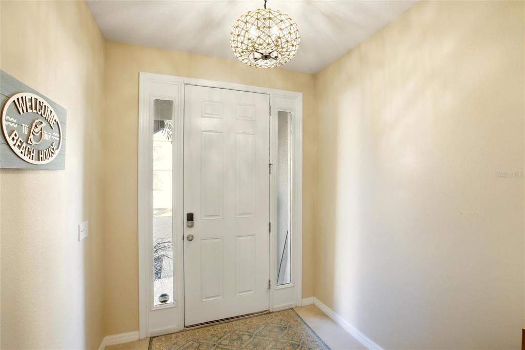 An entryway features a white front door with sidelights, a decorative light fixture, and tile flooring — 8660 PALMER PARK CIRCLE, SARASOTA, FL