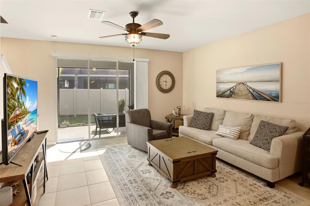 A living room features a beige sofa, a wooden coffee table, and a sliding glass door — 8660 PALMER PARK CIRCLE, SARASOTA, FL