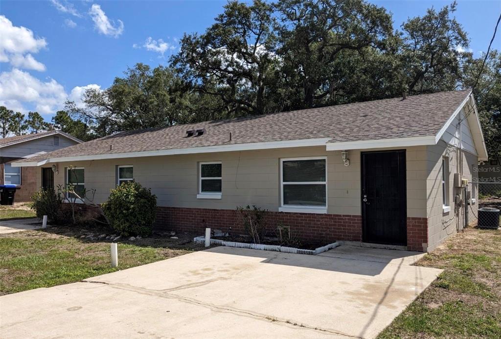 A single-story house with beige block walls, a brick base, and a concrete driveway — 511 N JOHN STREET, ORLANDO, FL