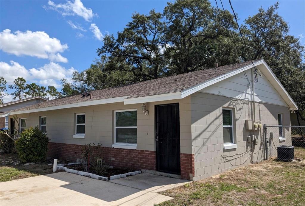 A single-story concrete block house with a brick base, a shingled roof, and a driveway — 511 N JOHN STREET, ORLANDO, FL