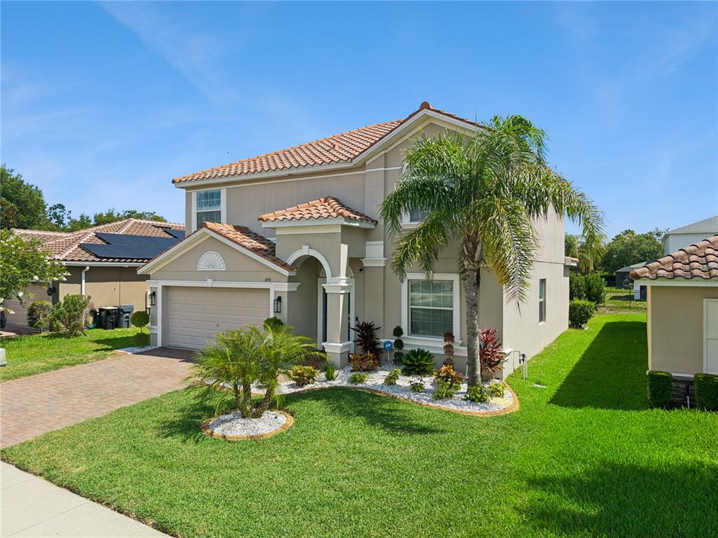 A two-story suburban house with a tile roof, beige stucco exterior, and a palm tree — 1454 LAKE SIDE AVENUE, DAVENPORT, FL
