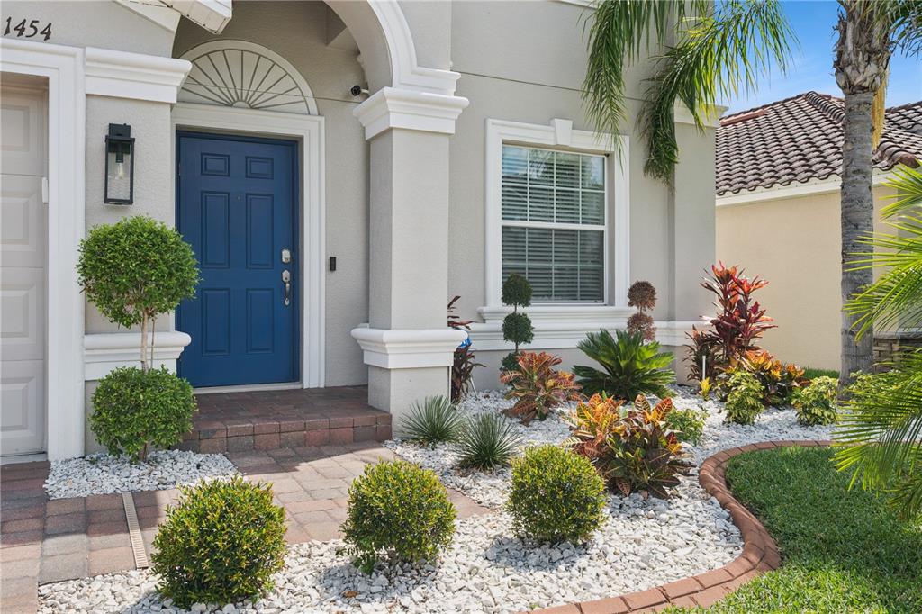 The exterior of a house features a blue front door, white trim, and landscaped garden — 1454 LAKE SIDE AVENUE, DAVENPORT, FL