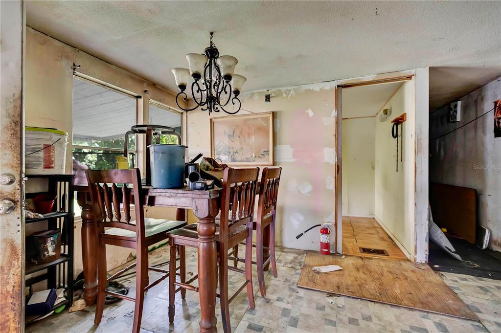 A dining area features a wooden table, chairs, a chandelier, and unfinished wall surfaces — 2614 KYLE STREET, LAKELAND, FL
