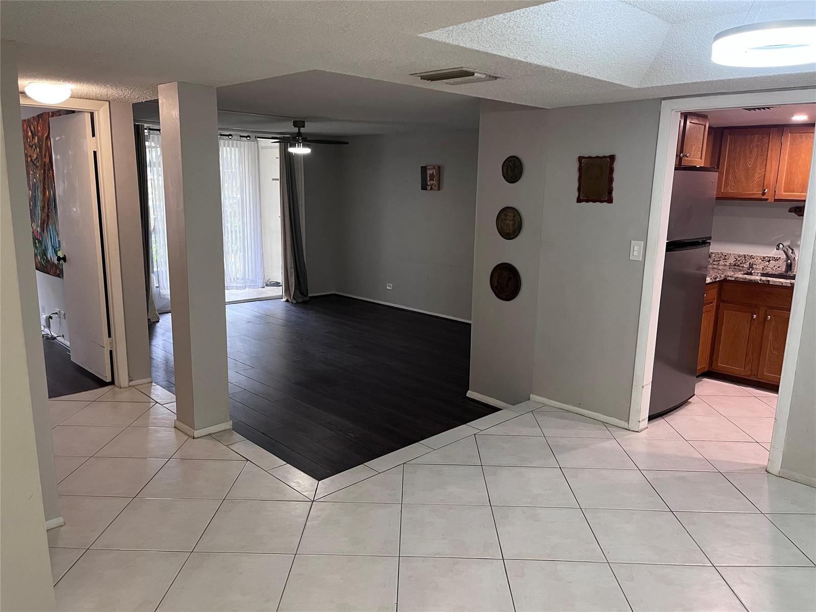 An open-concept living area features dark wood flooring, light tile, and an adjacent kitchen — 3670 N Inverrary Drive # 1F, Lauderhill FL 33319, LAUDERHILL, FL