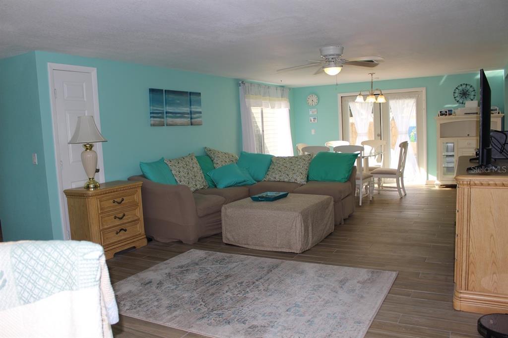 A living room with light blue walls, a sectional sofa, and a dining area — 658 ROANOKE STREET, DUNEDIN, FL