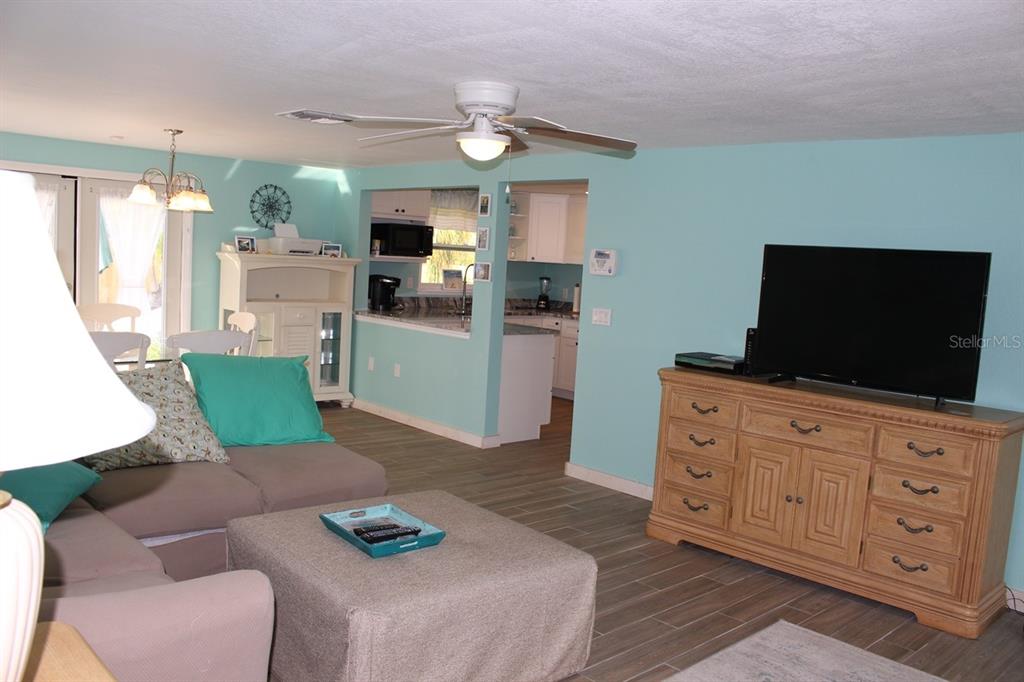 A living room with light blue walls, a beige sectional, and a wooden media console — 658 ROANOKE STREET, DUNEDIN, FL