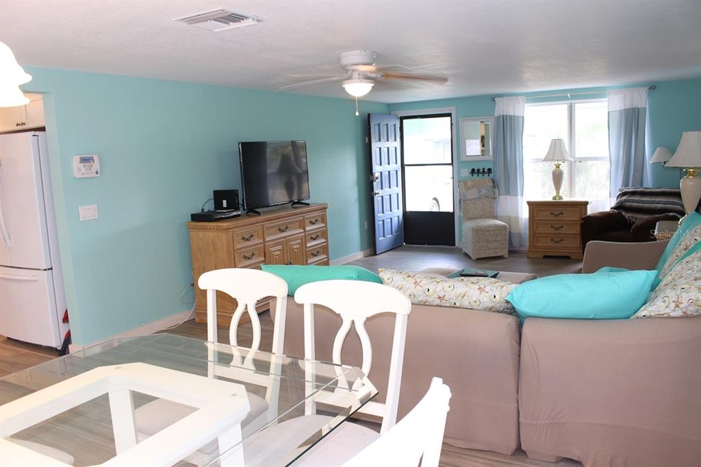 A living room with light blue walls, a ceiling fan, and a dining area — 658 ROANOKE STREET, DUNEDIN, FL