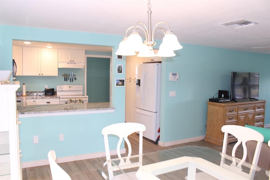 A dining area with a chandelier, light blue walls, and an open view into the kitchen — 658 ROANOKE STREET, DUNEDIN, FL
