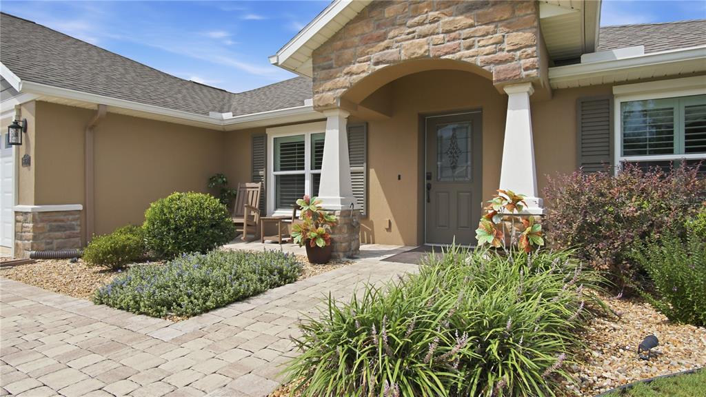 The exterior of a house features a stone-accented entryway, a paved walkway, and landscaping — 6752 SW 179TH COURT ROAD, DUNNELLON, FL