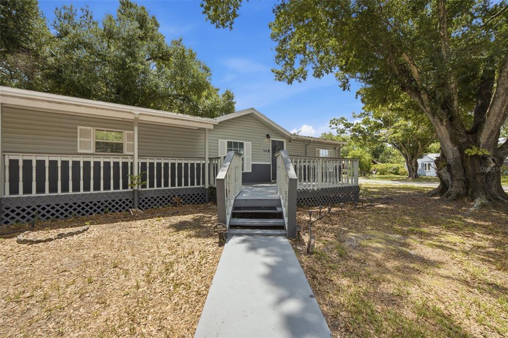 A light-colored manufactured home features a front deck with stairs and a concrete walkway — 5203 N MENDENHALL DRIVE, TAMPA, FL
