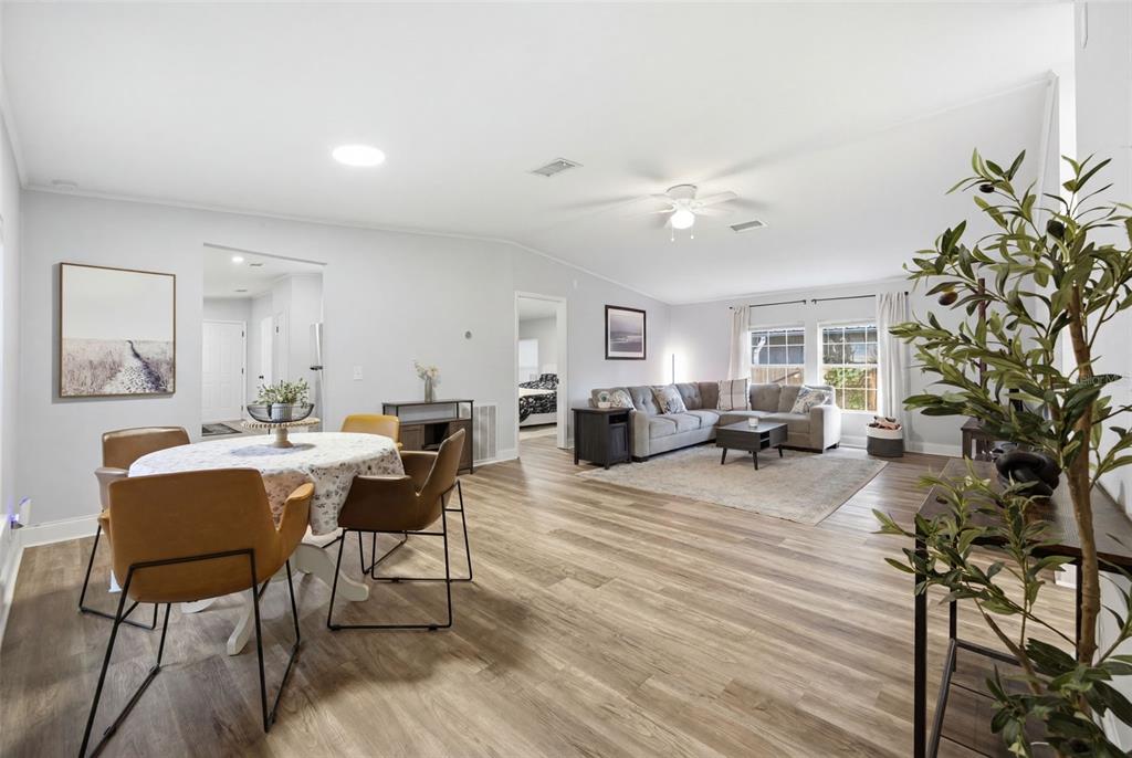 An open-concept living and dining area features light wood-look flooring and a neutral color palette — 5203 N MENDENHALL DRIVE, TAMPA, FL