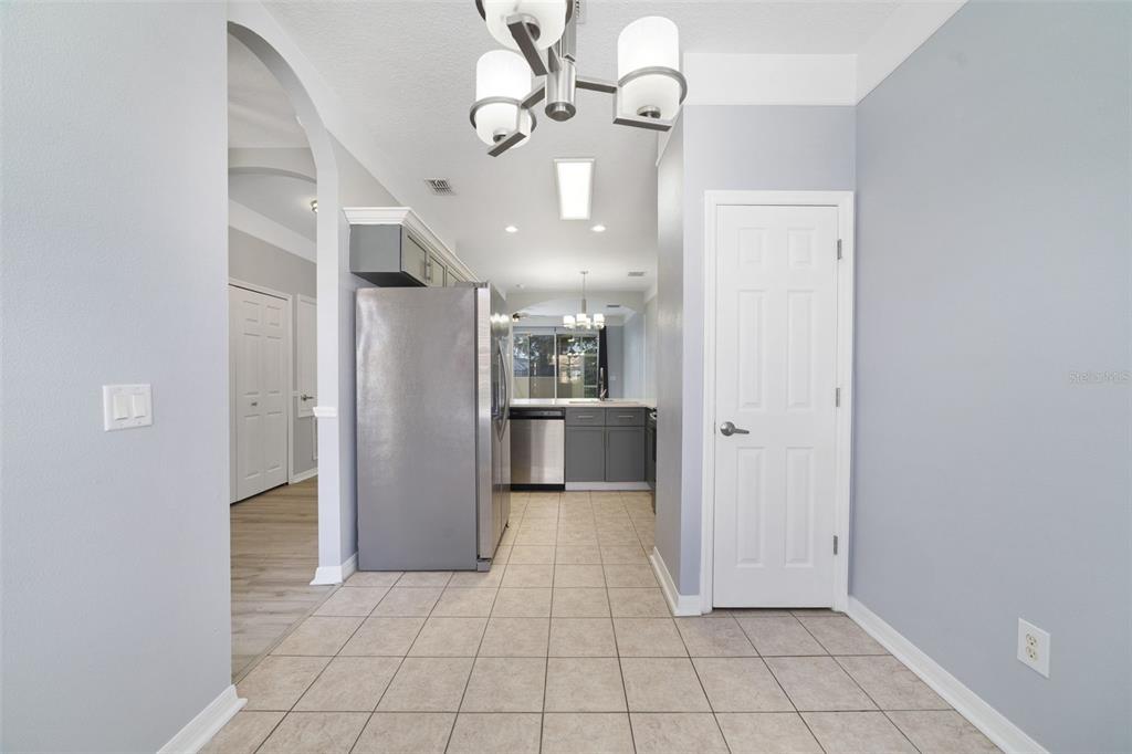 A kitchen with gray cabinets, stainless steel appliances, and tile flooring viewed from a hallway — 1236 SOUTH BEACH CIRCLE, KISSIMMEE, FL