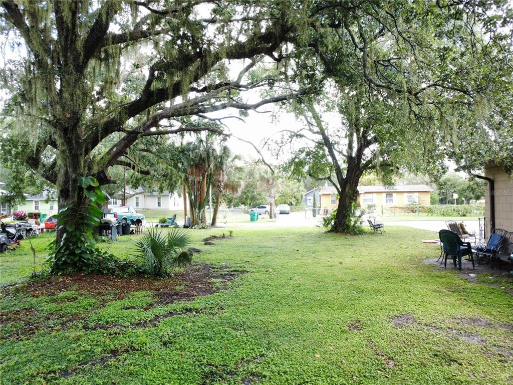 A grassy backyard features large, moss-covered oak trees and outdoor seating near a house — 188 MARY STREET, WINTER GARDEN, FL