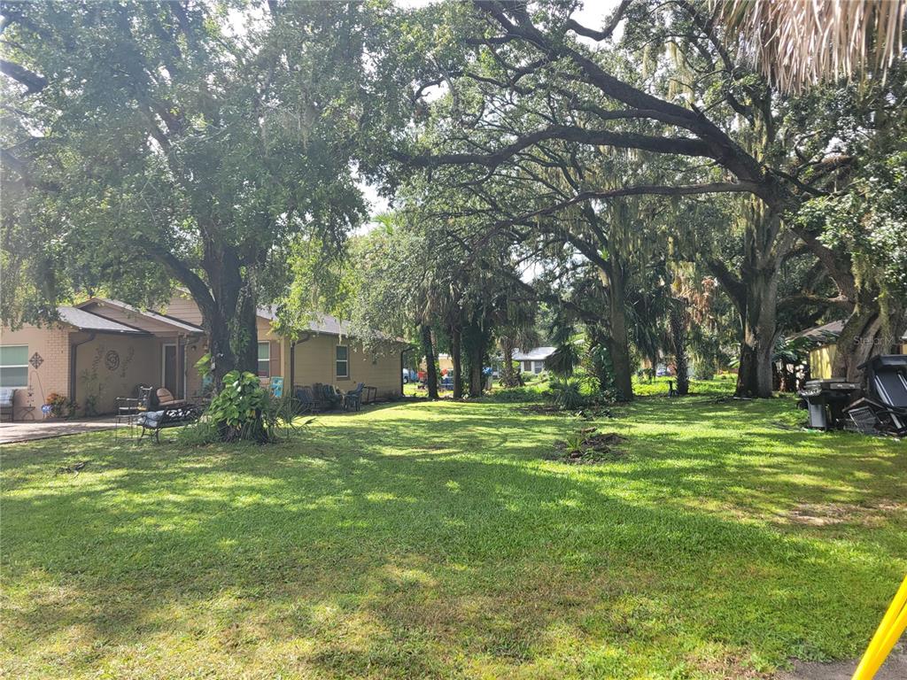 A grassy backyard features large oak trees, a patio area, and a tan house exterior — 188 MARY STREET, WINTER GARDEN, FL