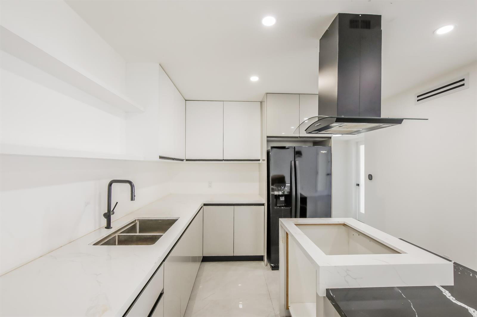 A modern kitchen features white cabinets, marble-look countertops, a black refrigerator, and a central island — 4701 SW 7th Street, Miami FL 33134, MIAMI, FL