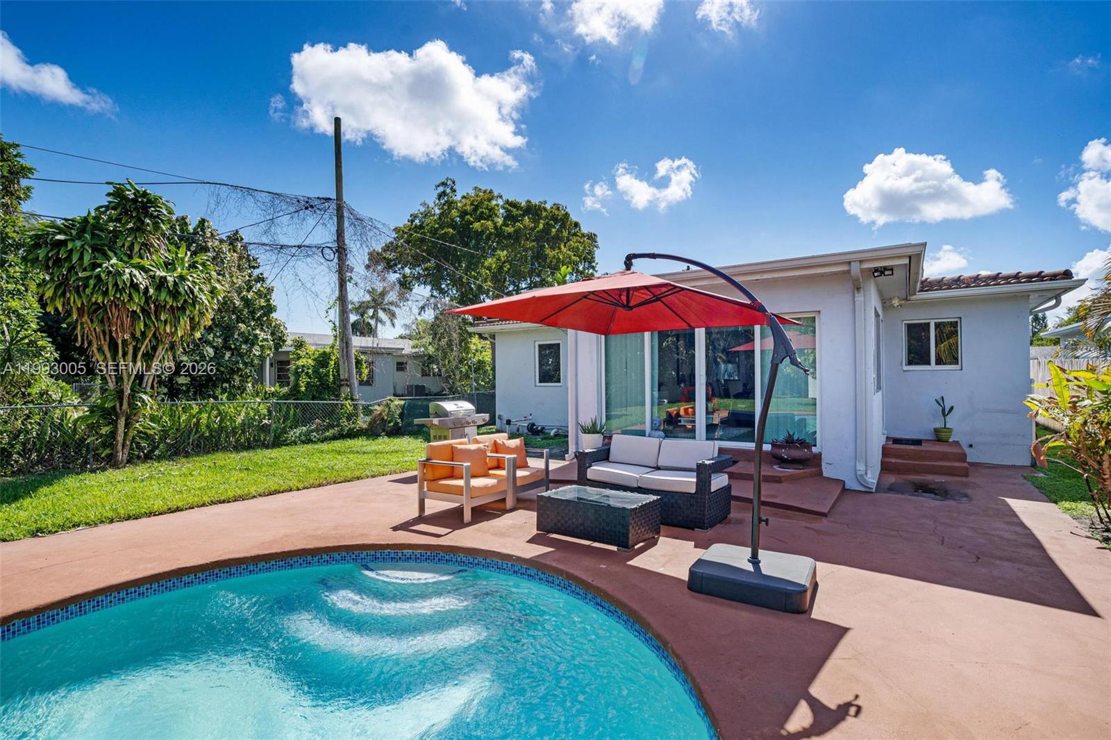 A backyard patio features a swimming pool, outdoor furniture, and a red cantilever umbrella — 2923 Madison St, Hollywood FL 33020, HOLLYWOOD, FL
