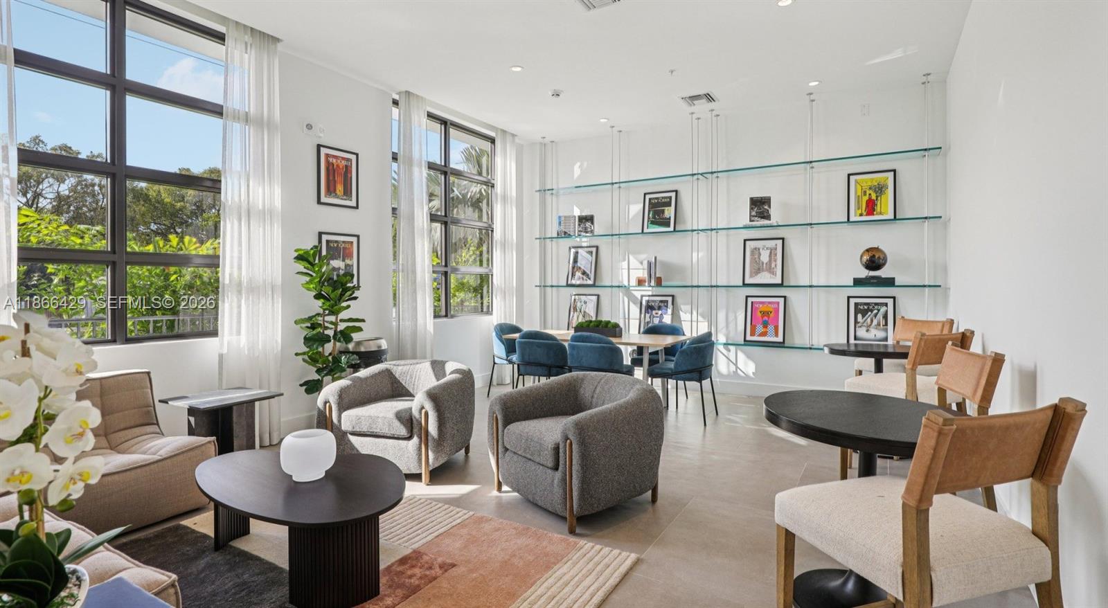 A bright, modern lounge area features glass shelving, multiple seating arrangements, and large floor-to-ceiling windows — 4465 Griffin Road, Davie FL 33314, DAVIE, FL