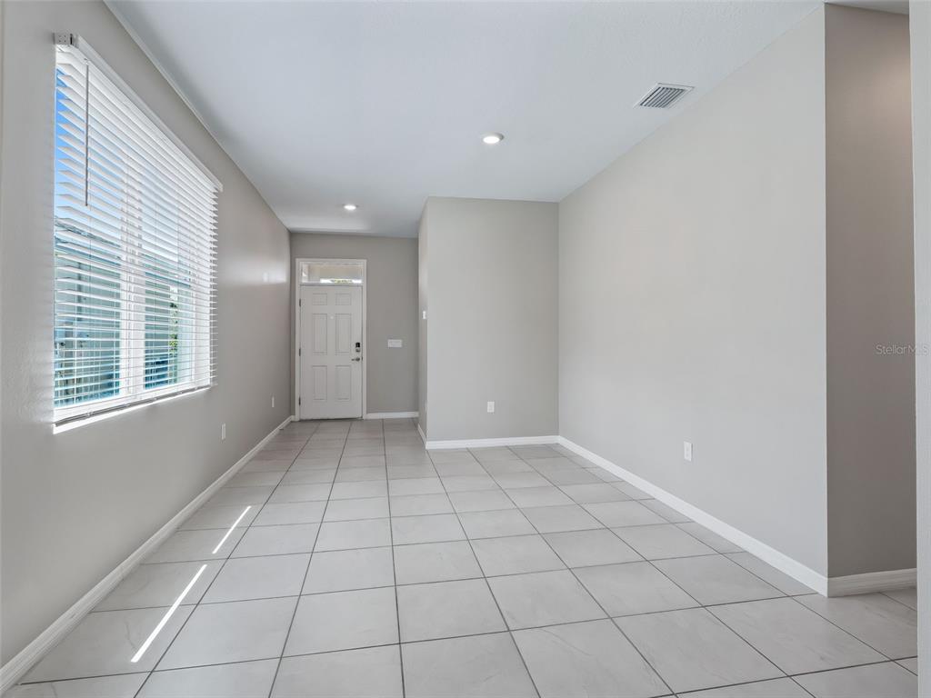 An empty room with light gray walls, tile flooring, and a window with white blinds — 5072 STOKES WAY, WILDWOOD, FL