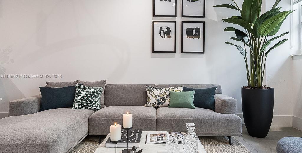A gray sectional sofa sits in a living room with framed art and a potted plant — 2001 Biscayne Blvd # 2104, Miami FL 33137, MIAMI, FL