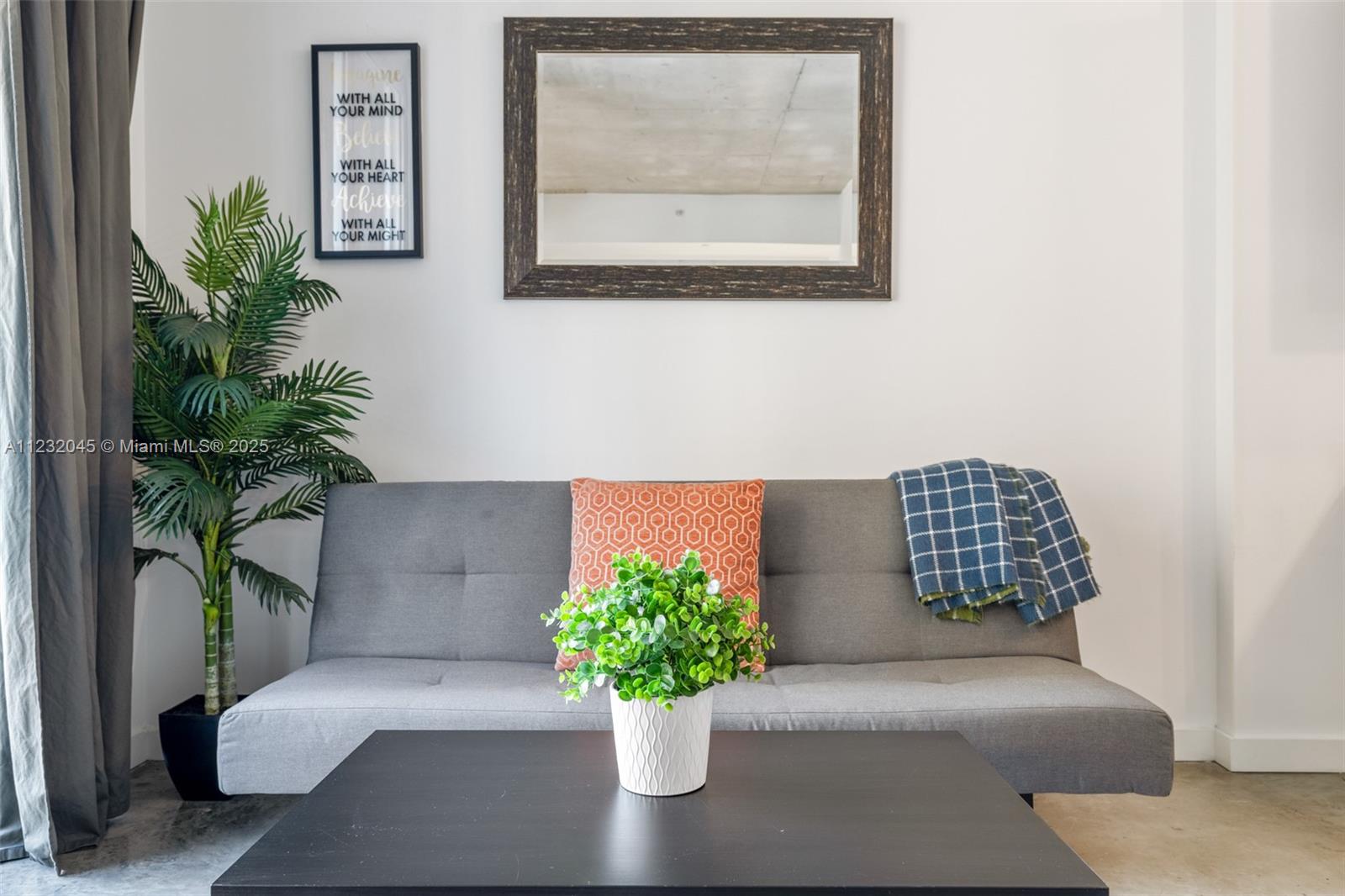 A gray sofa sits in front of a mirror, a plant, and a coffee table — 151 SE 1st St # 809, Miami FL 33131, MIAMI, FL