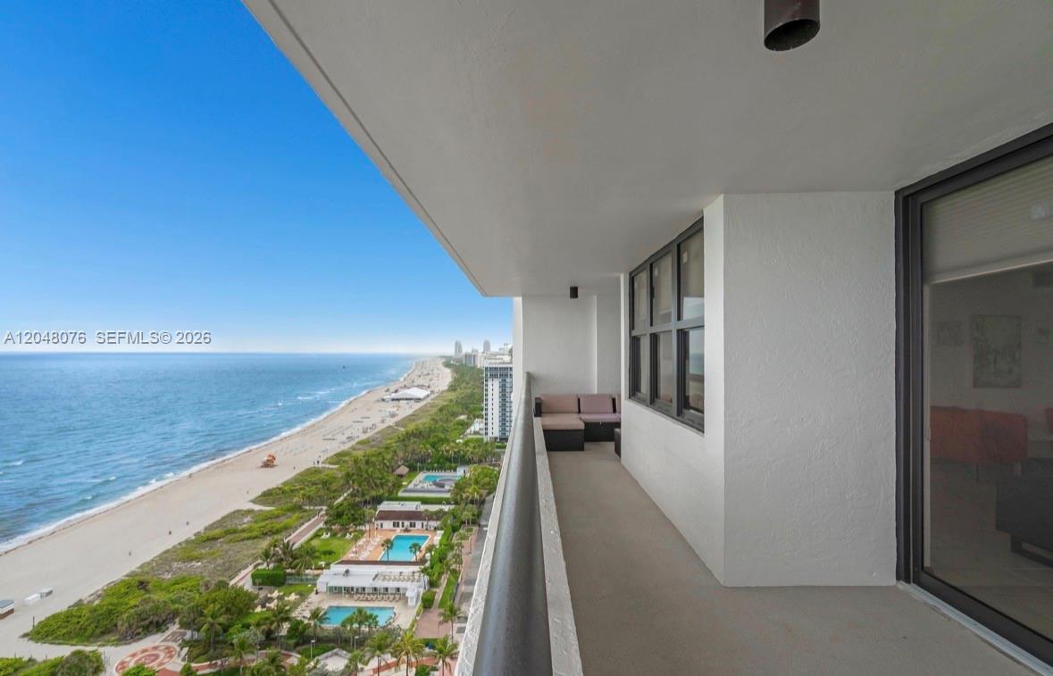 A high-rise balcony overlooks a sandy beach, ocean, and swimming pools below — 2555 Collins Ave # 1101, Miami Beach FL 33140, MIAMI BEACH, FL