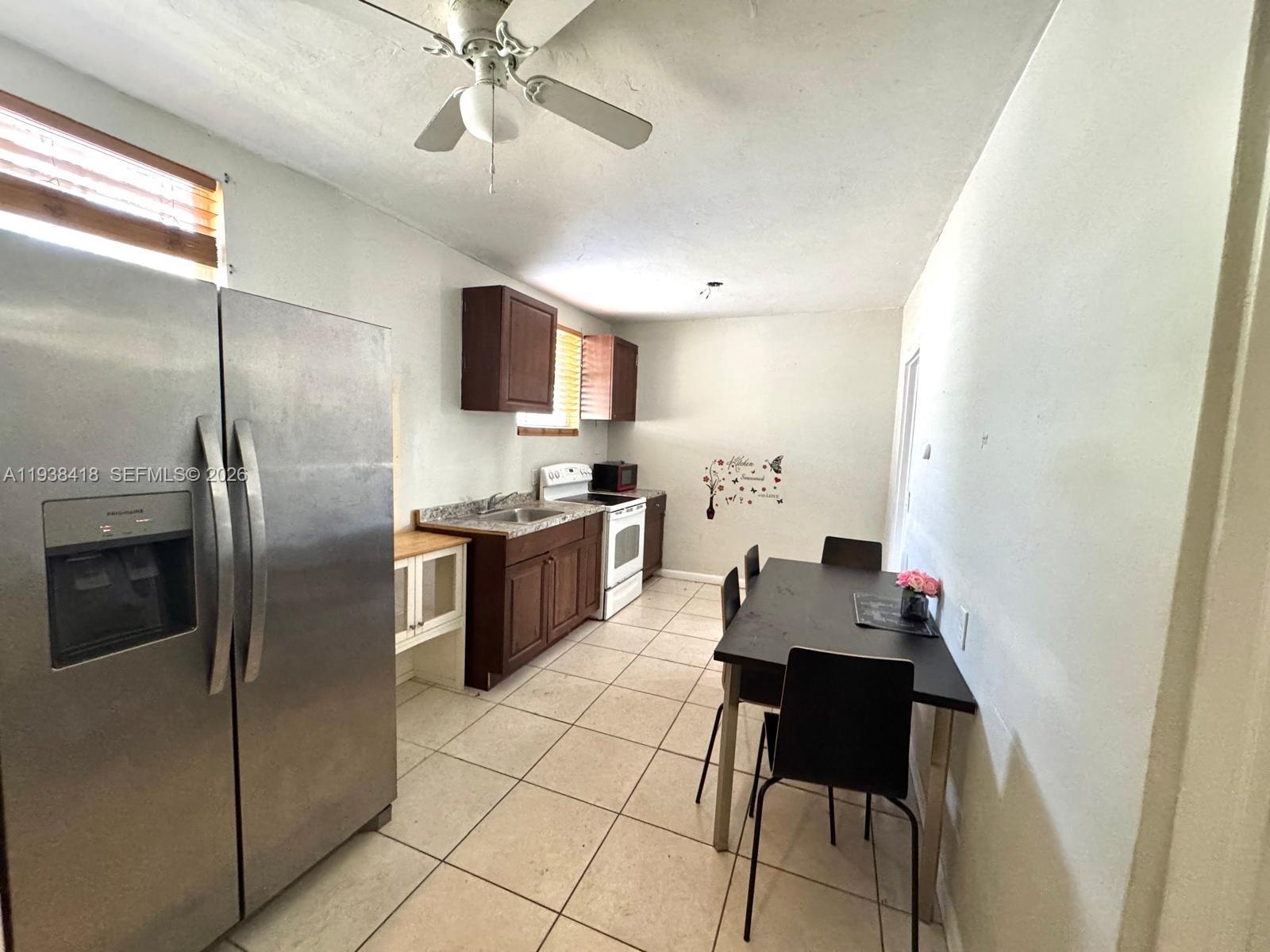 A kitchen features stainless steel appliances, dark wood cabinets, and a dining table with chairs — 465 NE 157th Ter # 2, Miami FL 33162, MIAMI, FL