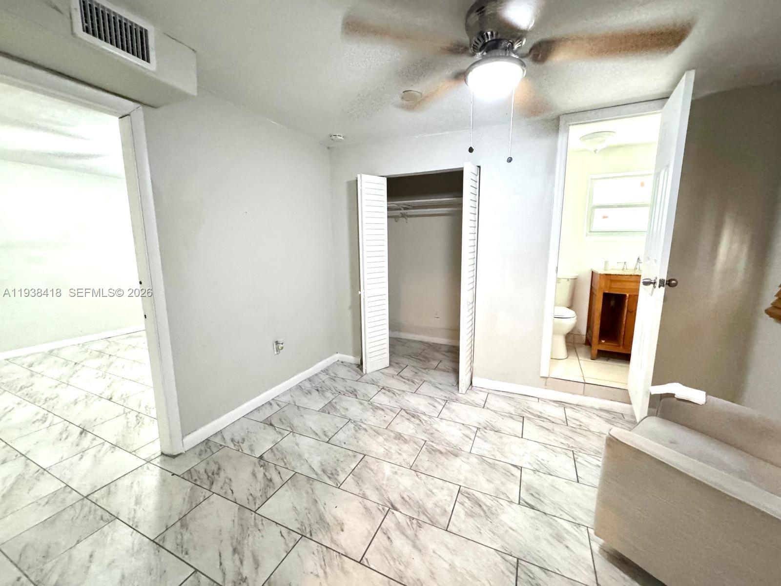 A bedroom features light gray walls, marble-patterned tile flooring, a ceiling fan, and an attached bathroom — 465 NE 157th Ter # 2, Miami FL 33162, MIAMI, FL