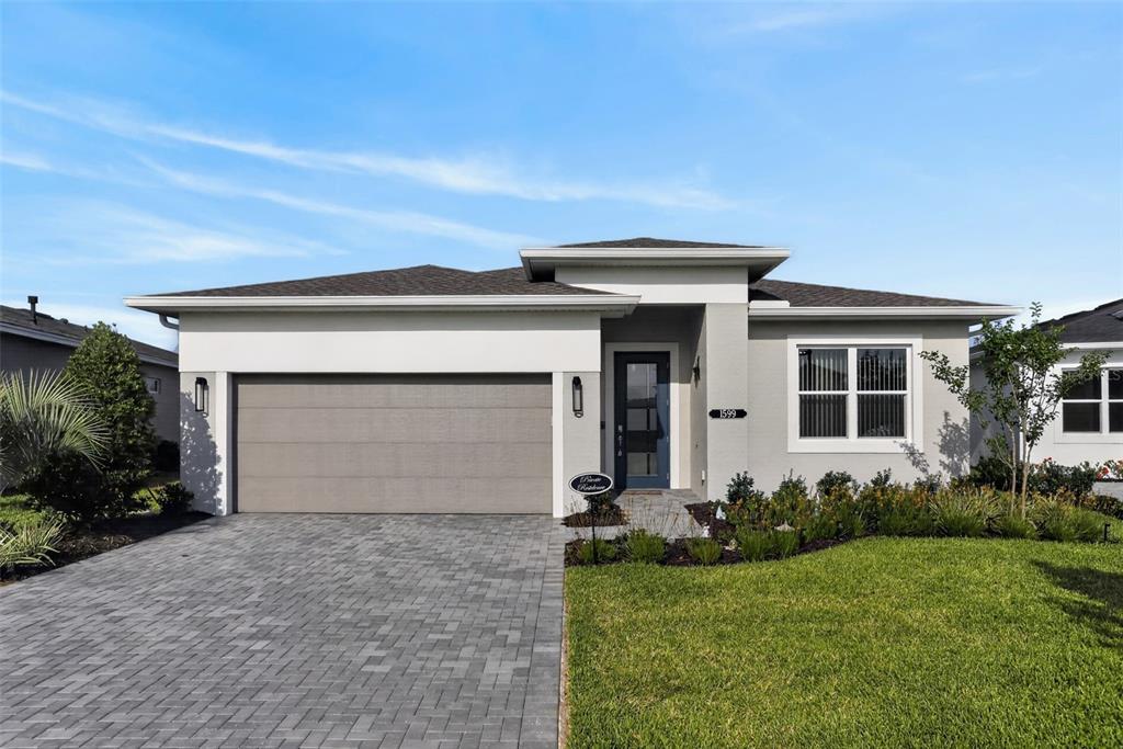 The rear exterior of a single-story house features a screened-in lanai and a grassy yard — 1599 BELLAGIO LOOP, TAVARES, FL