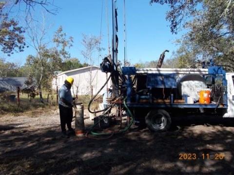 A worker operates a truck-mounted drilling rig on a wooded lot — HAGAR DRIVE, NEW PORT RICHEY, FL