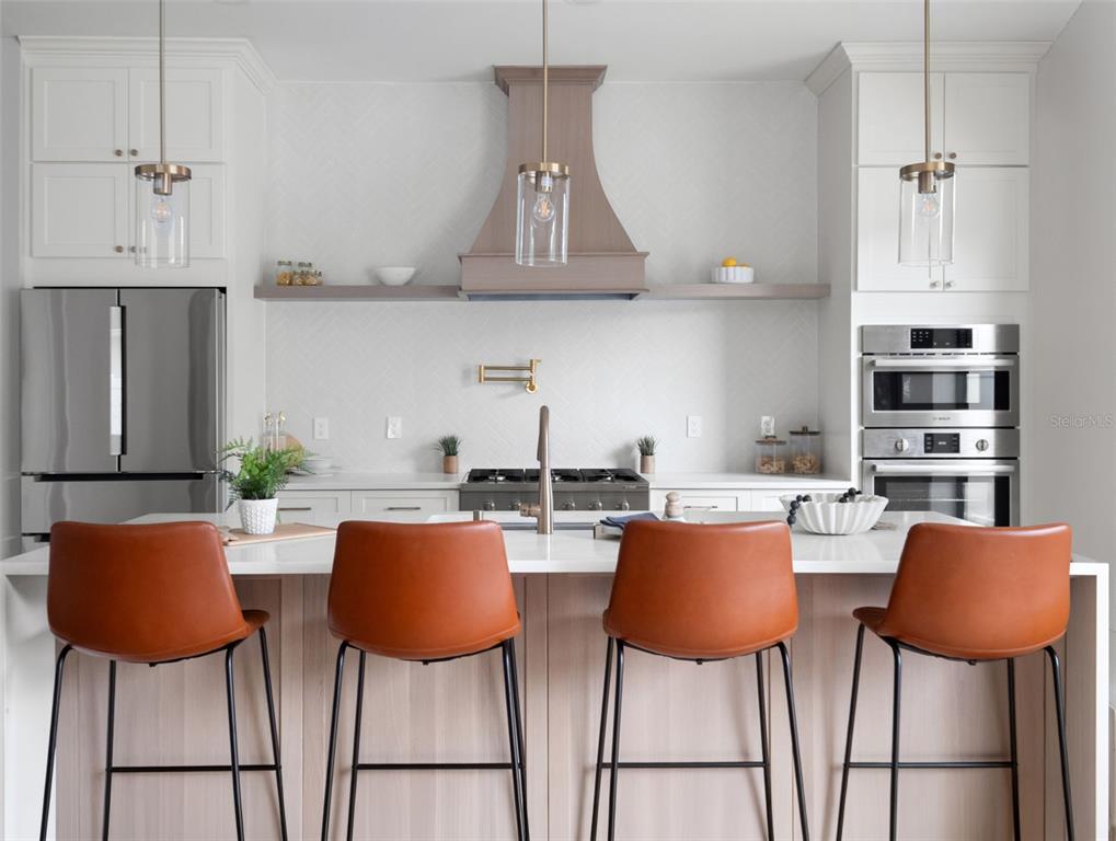 A modern kitchen features white cabinetry, a wood range hood, and four leather bar stools — 1000 N FOREST AVENUE, ORLANDO, FL
