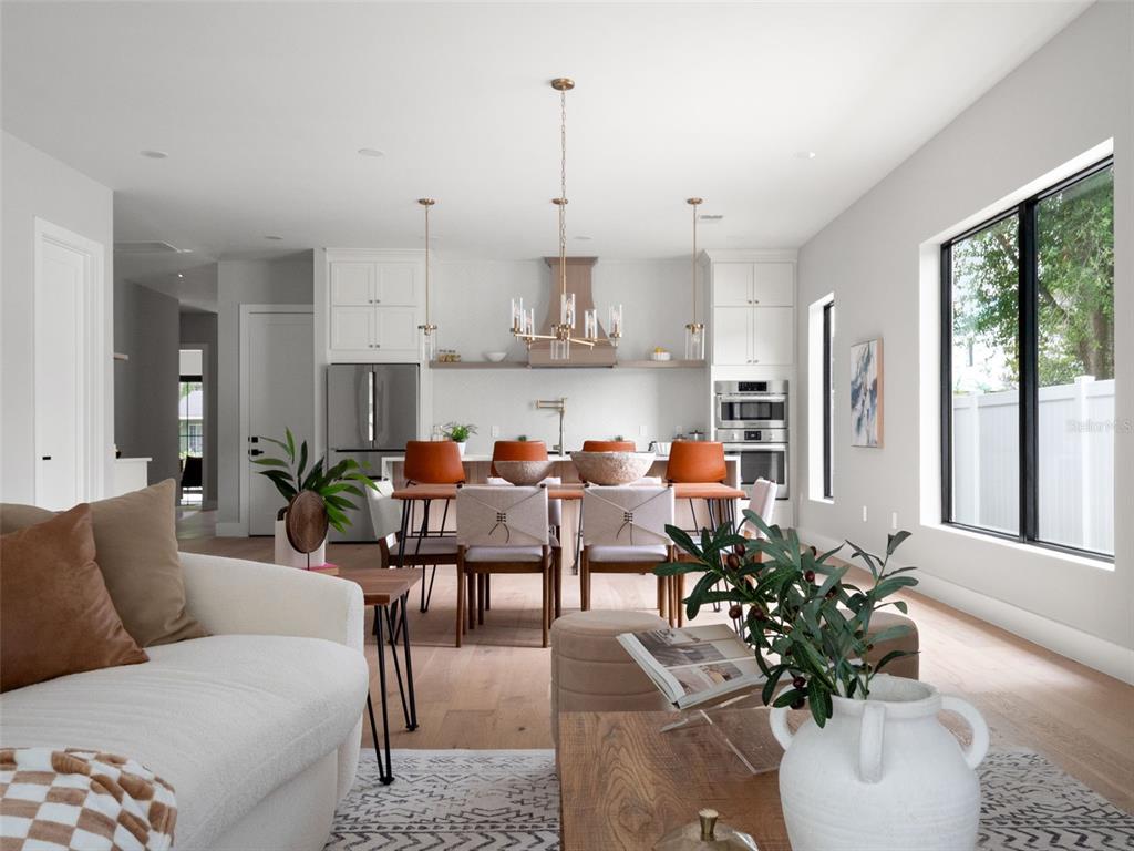 An open-concept kitchen and living area features white cabinetry, a dining table, and light wood flooring — 1000 N FOREST AVENUE, ORLANDO, FL