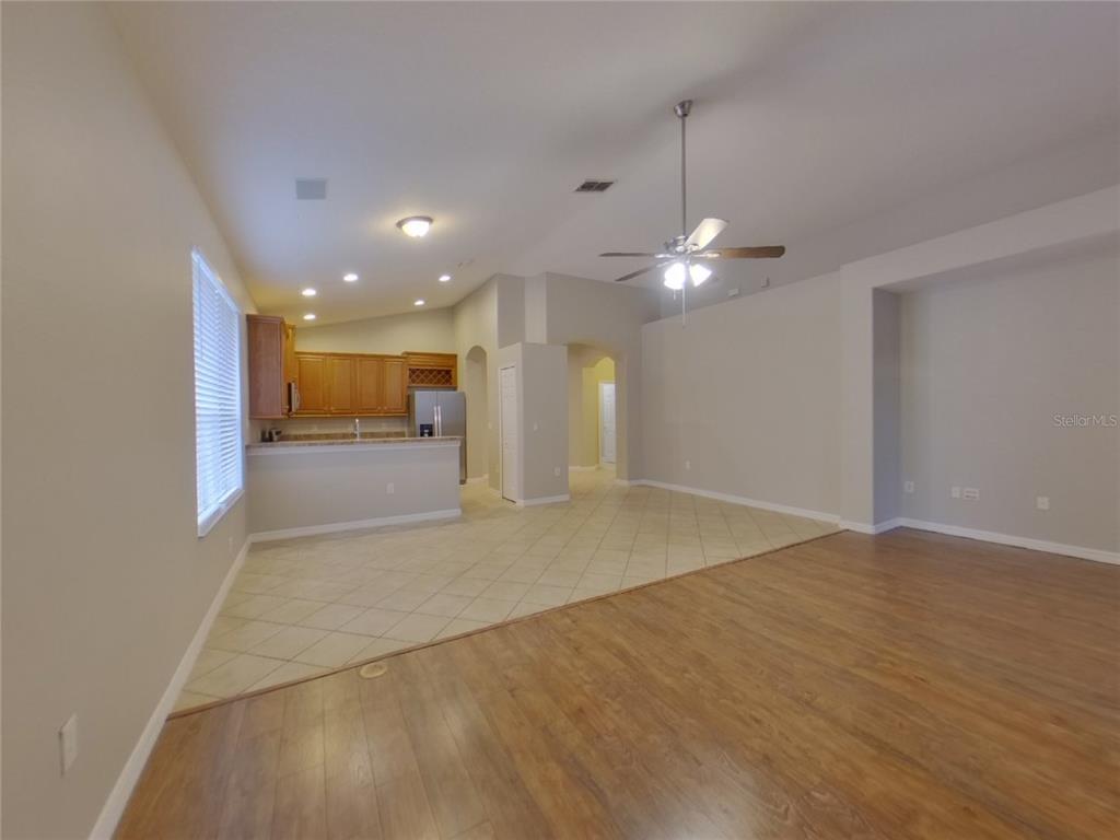 An open-concept living area features wood-look flooring, a tiled kitchen space, and a ceiling fan — 351 FAIRMOUNT PARK COURT, DELAND, FL