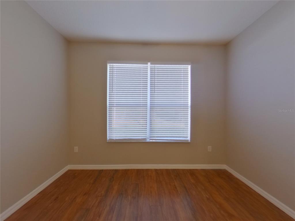 An empty room with light-colored walls, wood-look flooring, and a window with white blinds — 351 FAIRMOUNT PARK COURT, DELAND, FL