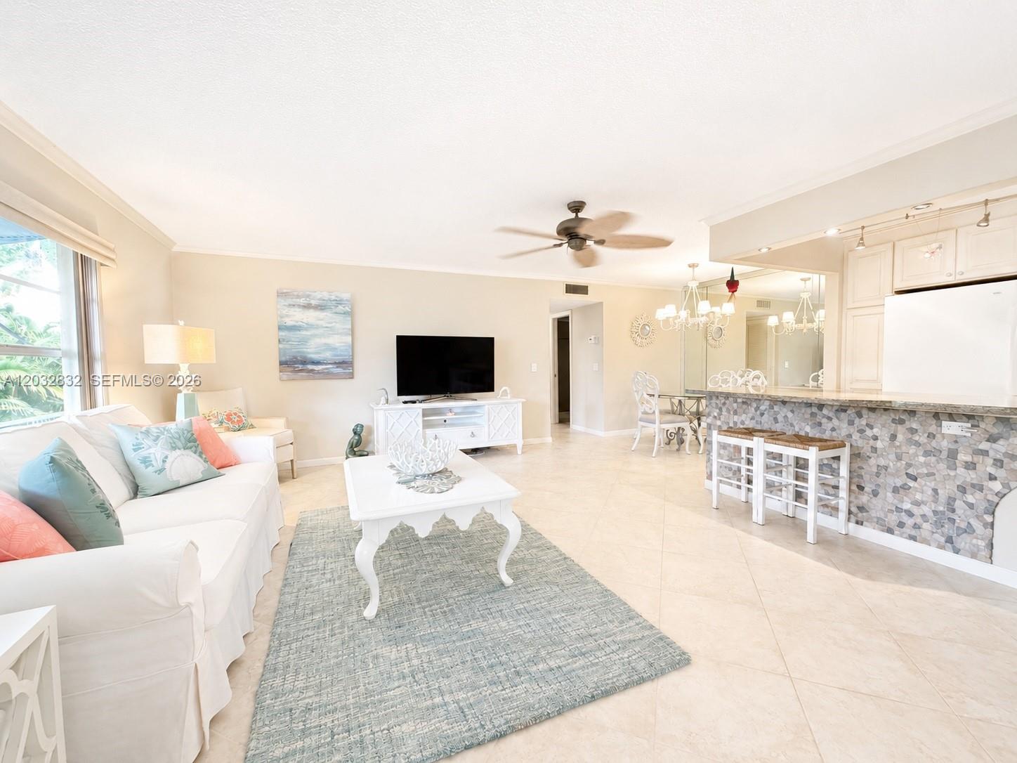 A living room and kitchen area with tile floors, white furniture, and a breakfast bar — 1042 North Dr # A, Delray Beach FL 33445, DELRAY BEACH, FL