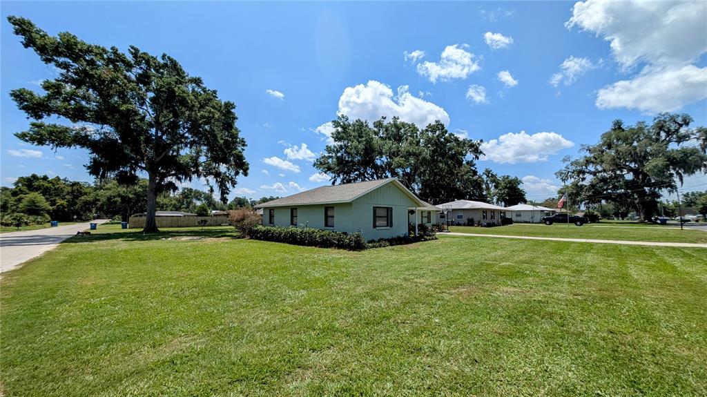 A light-colored, single-story house sits on a large, grassy lot with mature trees — 624 N LANIER AVENUE, FORT MEADE, FL