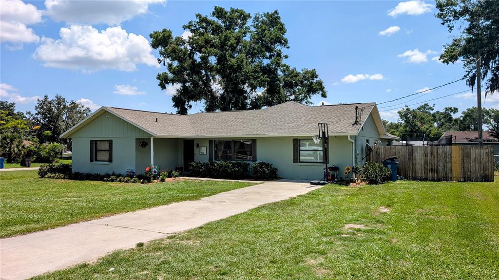 A single-story house with light green siding, a concrete driveway, and a wooden fence — 624 N LANIER AVENUE, FORT MEADE, FL