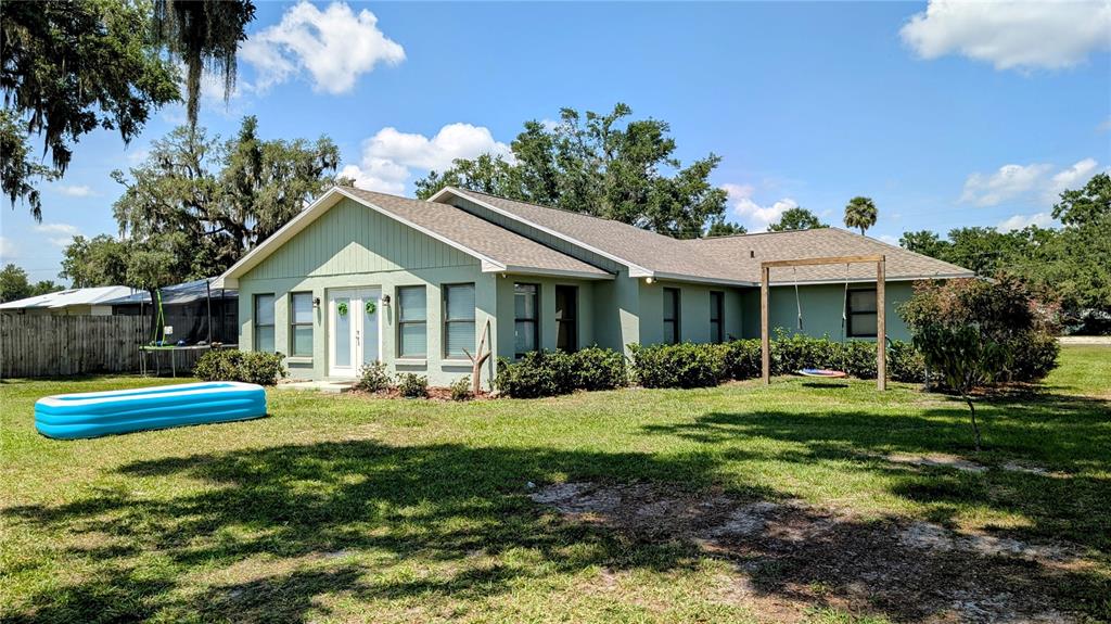 A light green house with a blue inflatable pool on the lawn and a swing — 624 N LANIER AVENUE, FORT MEADE, FL