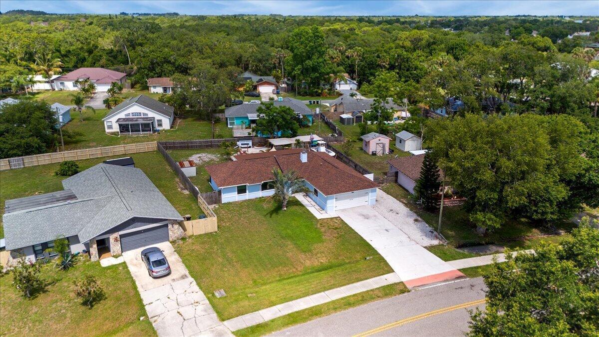 An aerial view shows a single-story house with a brown roof and a concrete driveway — 2350 Fallon Boulevard NE, Palm Bay FL 32907, PALM BAY, FL